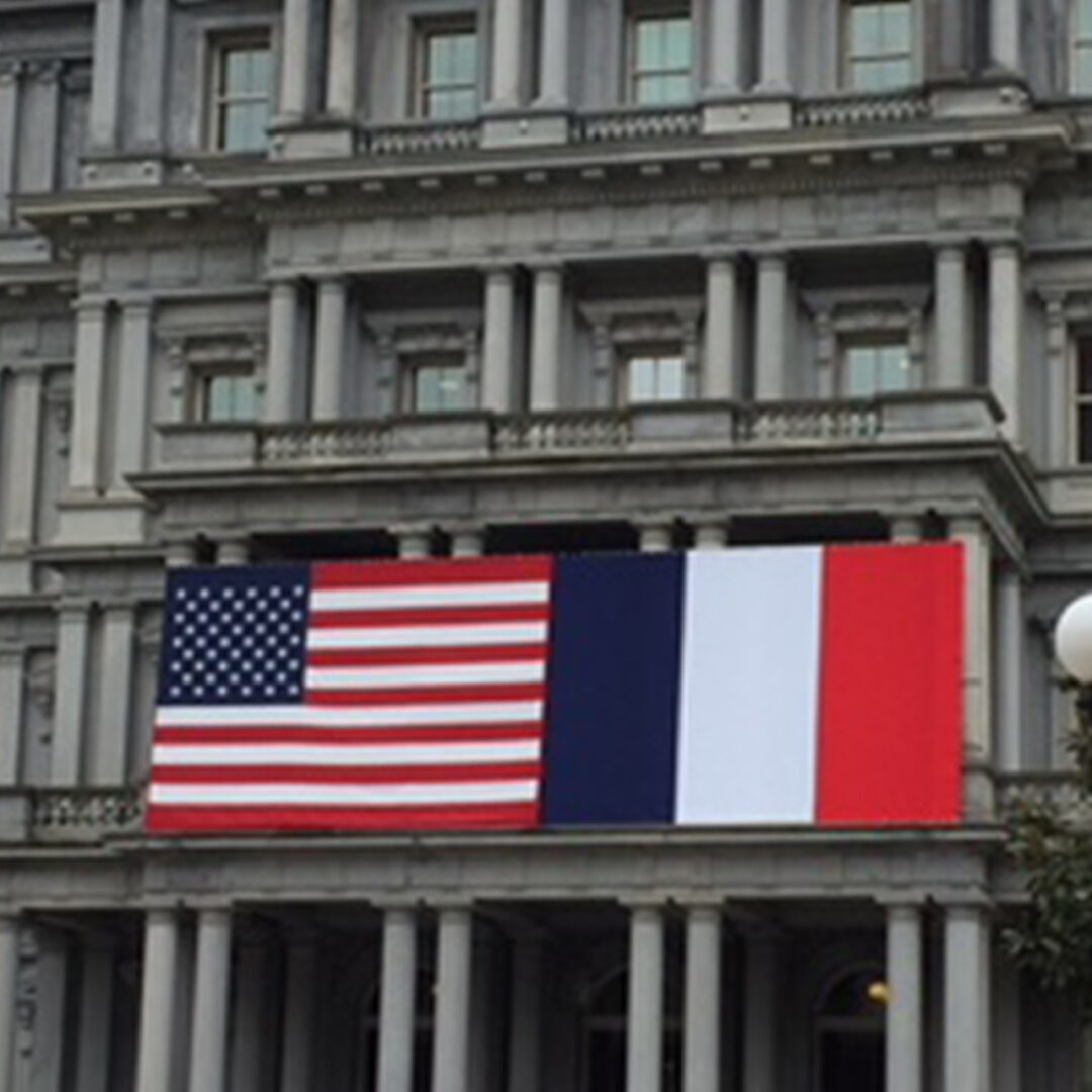 American and French flags displayed side by side on a building.