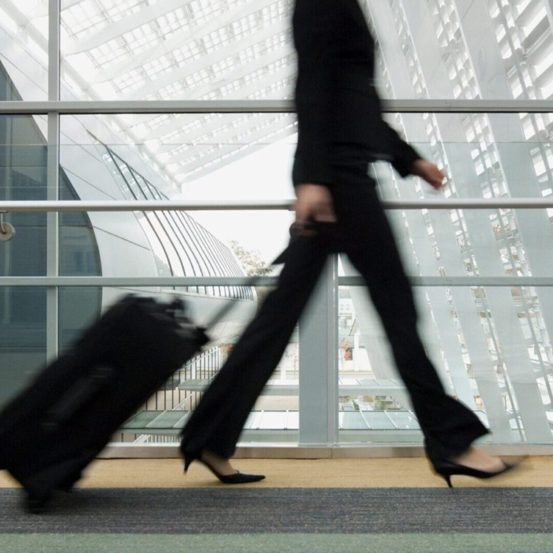 Business traveler walking briskly with a suitcase in an airport.