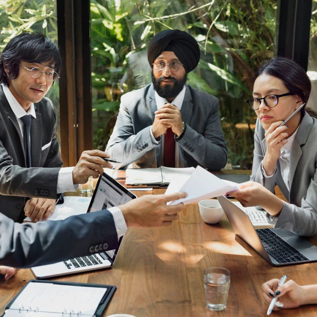 A diverse business team discussing documents around a conference table.