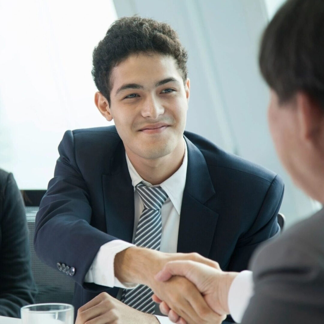 Two businessmen shaking hands in a formal meeting.
